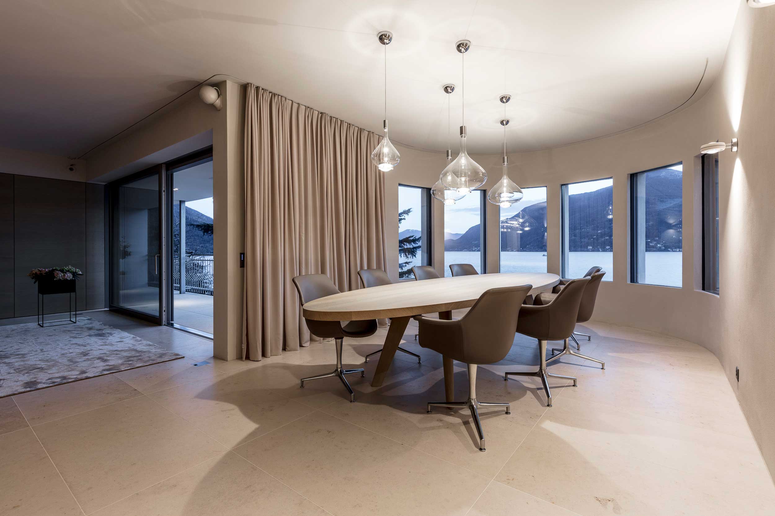 Schönes Wohnzimmer mit ovalem Tisch in der Mitte und schöne Lampen von oben runterhängend